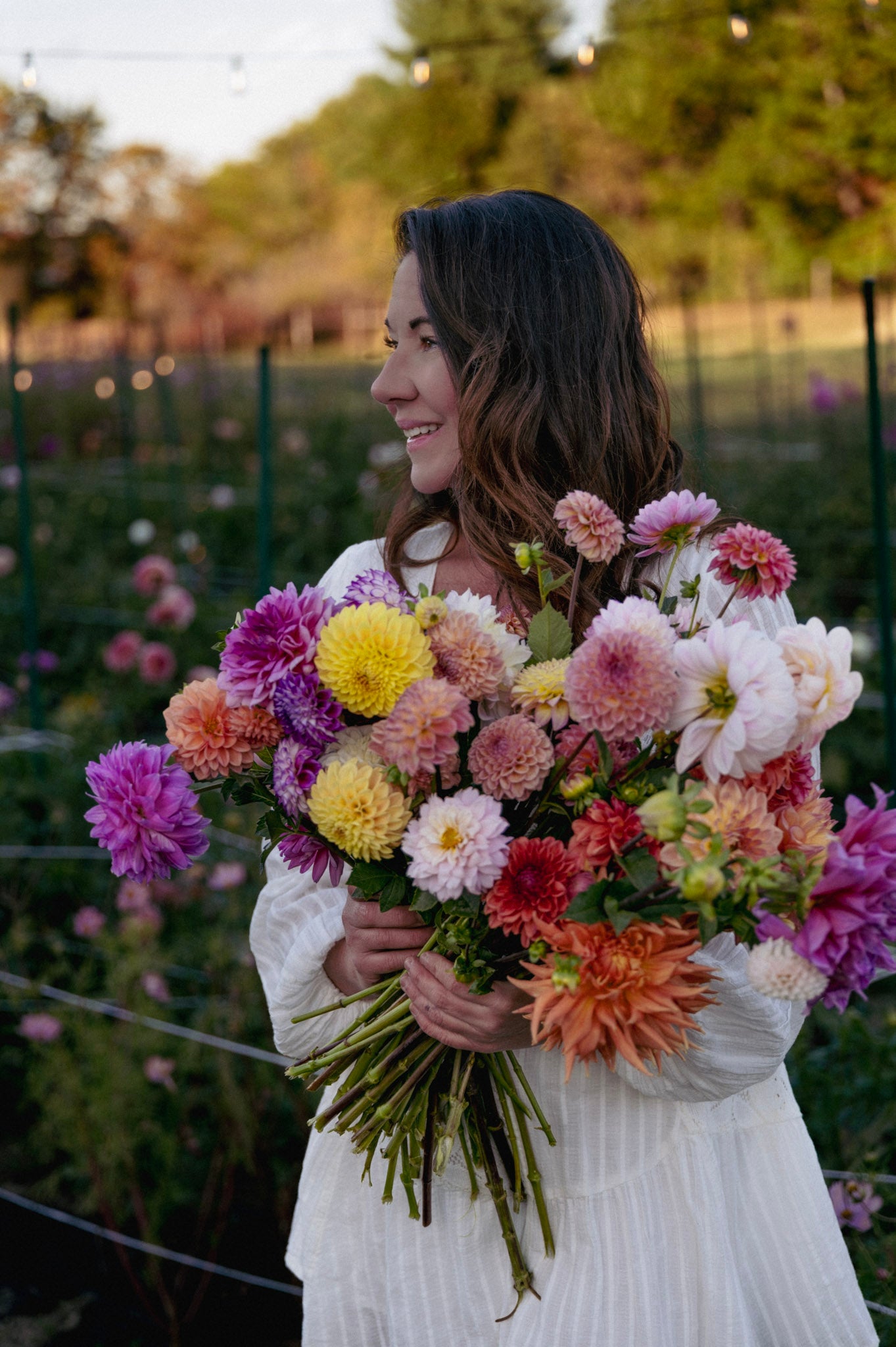 shannon from fox cottage farm holding a bouquet of dahlias their dahlia field